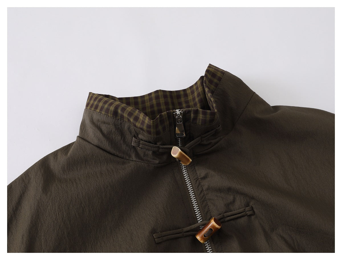 Upper front of a dark olive-brown jacket, showing its plaid-lined stand collar, zipper, and toggle closures.