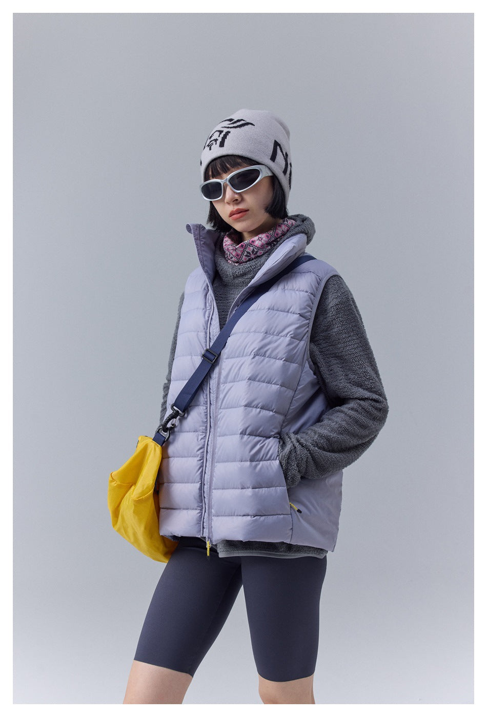 Three-quarter view of a model wearing a pale lavender quilted vest over a charcoal fleece.