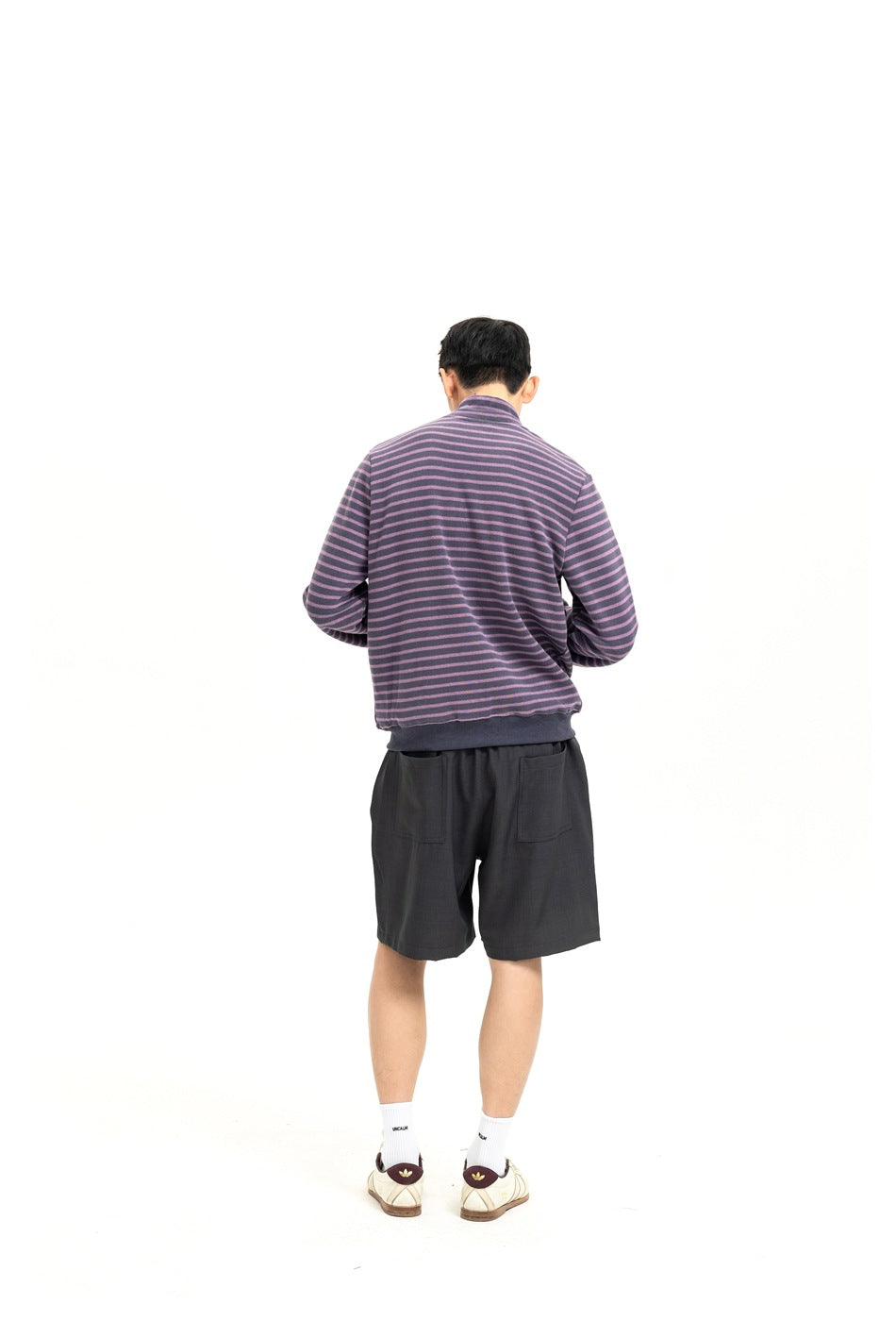 Back view of a model wearing charcoal shorts with two rear pockets and a purple-and-gray striped sweatshirt.