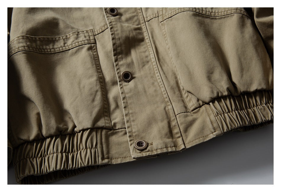 Close-up of a khaki jacket with a button placket, stitched panels, and a gathered elastic hem.