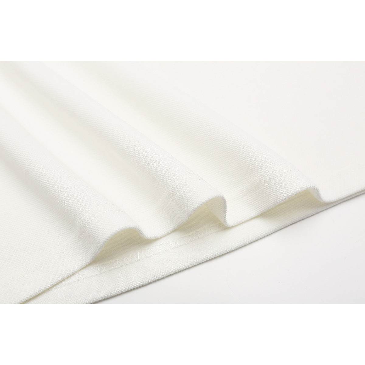 Close-up of off-white polo fabric folded to show its texture and stitched edge.
