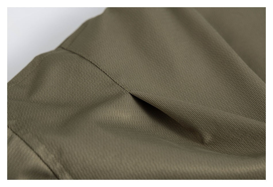 Close-up of an olive jacket seam and the fine texture of its fabric.