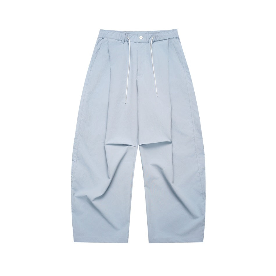 Light blue wide-leg pleated pants with drawstring waist and button front, flat lay