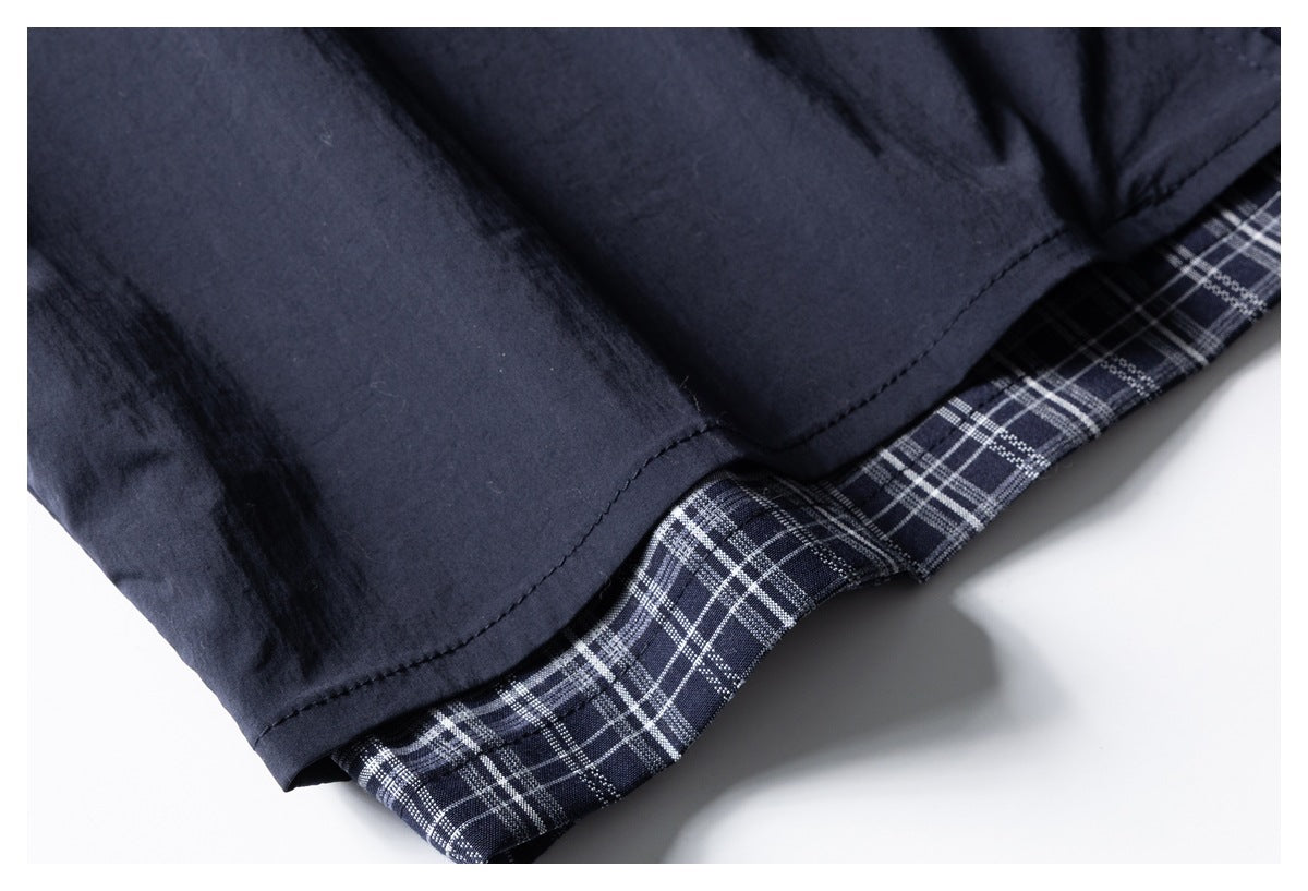 Close-up of the navy shirt hem with a white-and-gray plaid layer showing underneath.