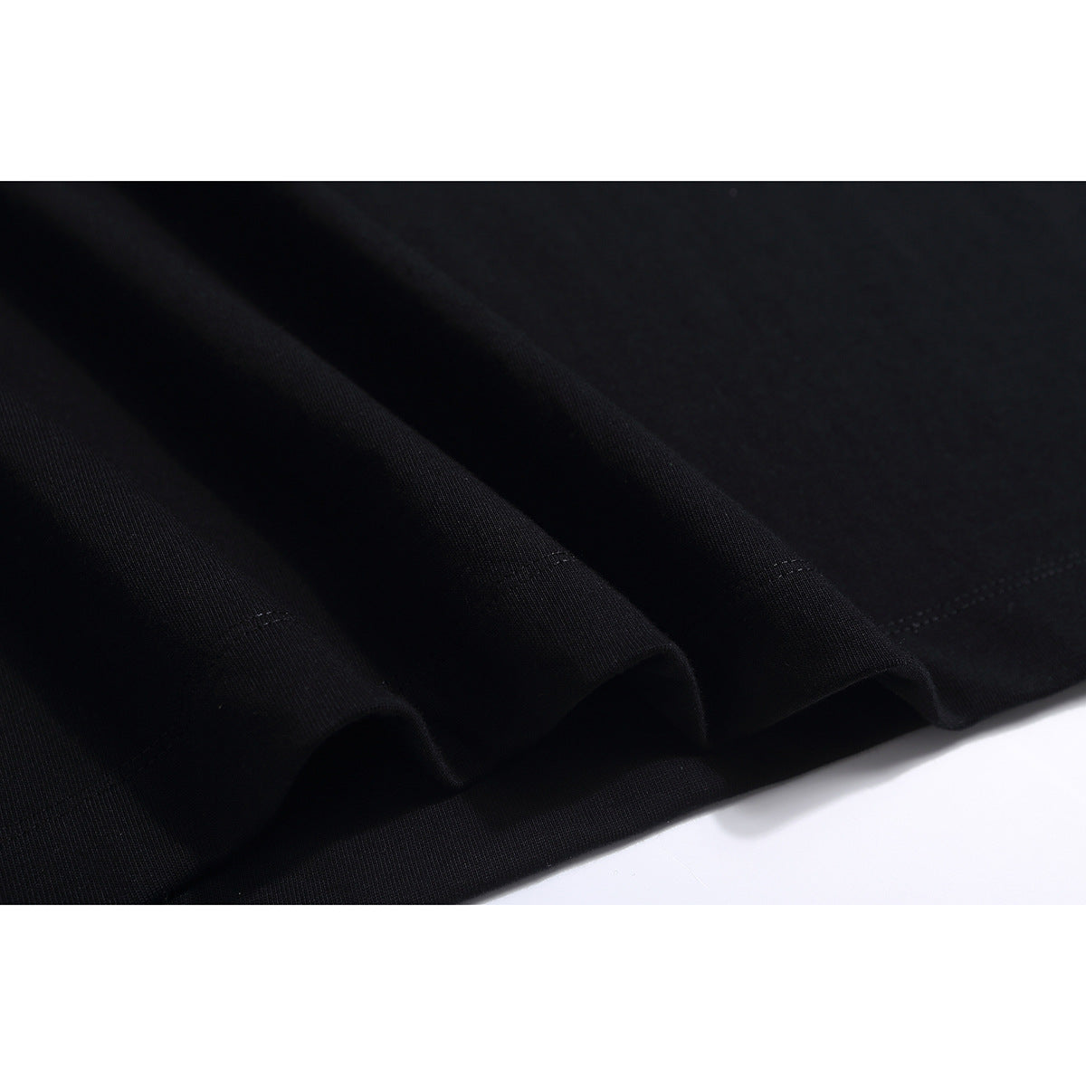 Close-up of black T-shirt fabric arranged in folds, showing the stitched hem.