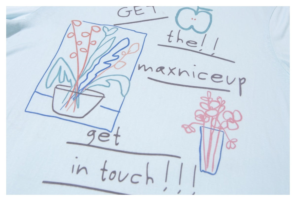 Close-up of a pale blue T-shirt print with handwritten English lettering and colorful flower illustrations.