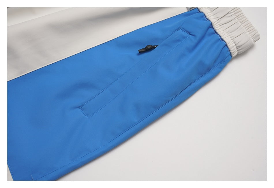 Close-up of a blue pant leg with a white panel, elastic ankle cuff and zip pocket.