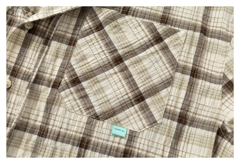 Close-up of the plaid shirt's chest pocket, buttons, and small turquoise label.