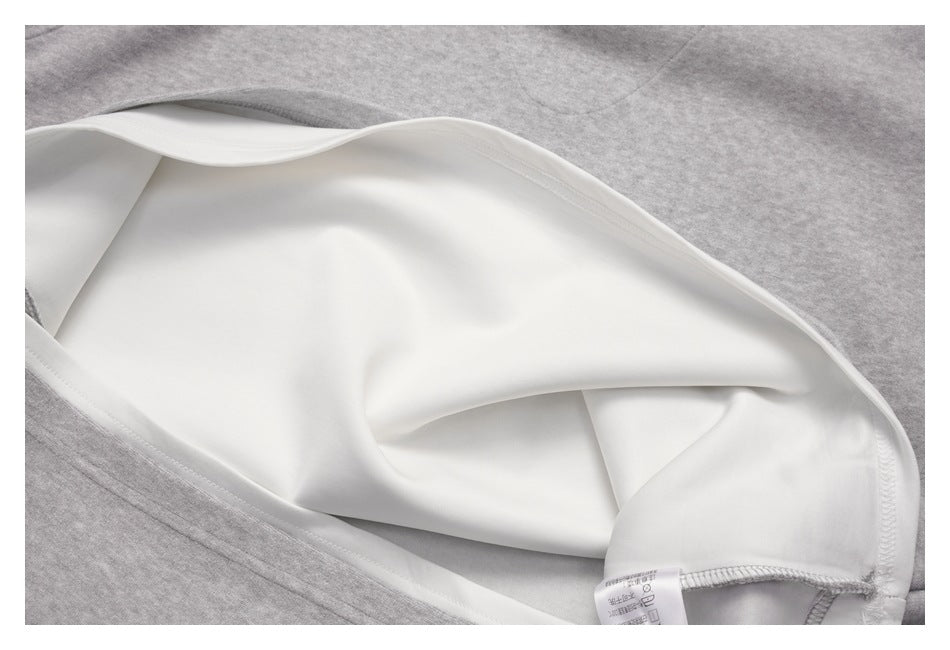 Inside view of a light gray top showing its white inner layer, stitching, and care label.