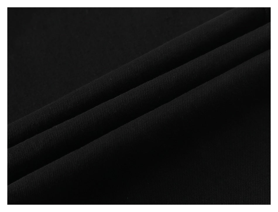 Close-up of black fabric folded into diagonal ridges, showing its fine woven texture.