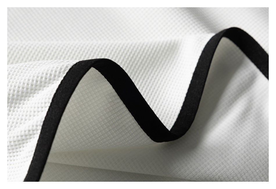 Folded white textured fabric showing its black bound edge and pale underside.