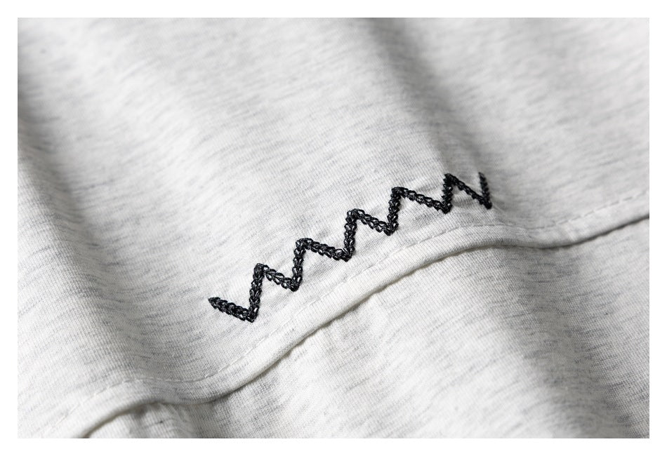 Close-up of black zigzag stitching on light gray heathered fabric.