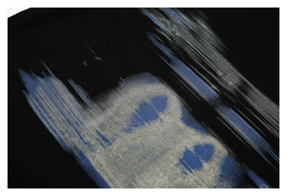 Close-up of black fabric with a large abstract gray and blue brushstroke print.