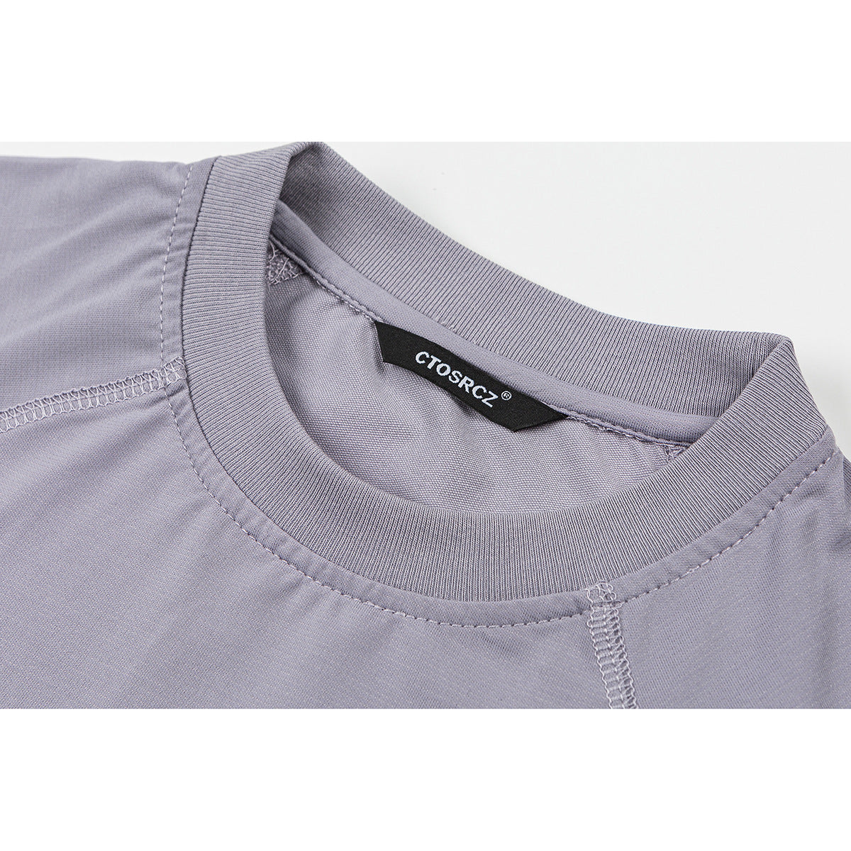 Close-up of a lavender-gray T-shirt neckline, ribbed collar, stitching, and sewn-in black brand label.