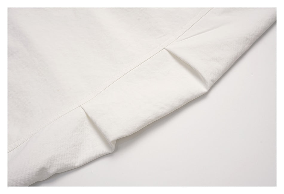 Close-up of an off-white garment seam and folded edge laid flat.