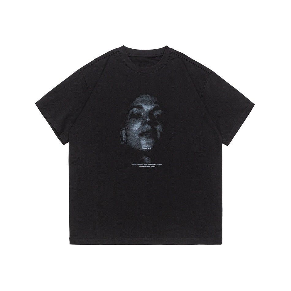 Black short-sleeve crewneck T-shirt with a grainy face portrait graphic and small text print on the chest