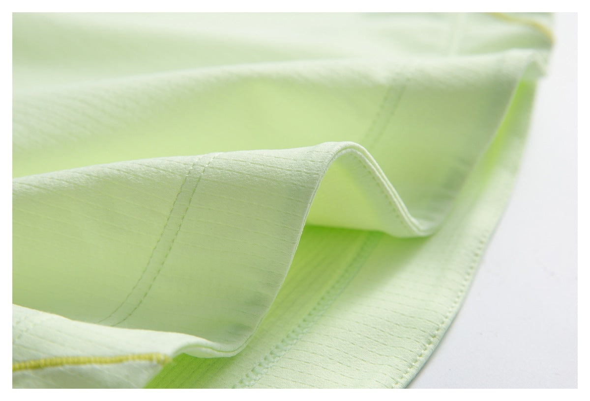 Close-up of pale lime garment fabric showing a folded edge and stitched seams.