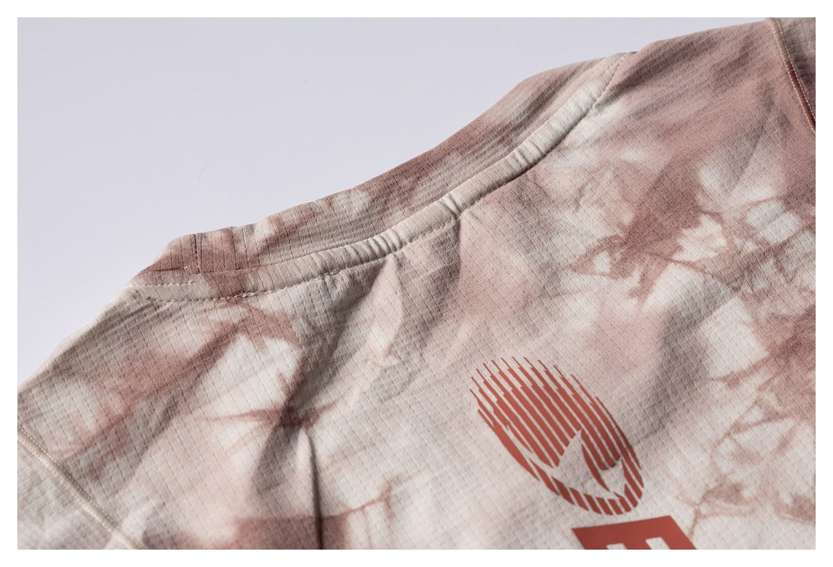 Close-up of the shirt's neckline and upper area, showing a cream and dusty-rose tie-dye pattern and partial red graphic.