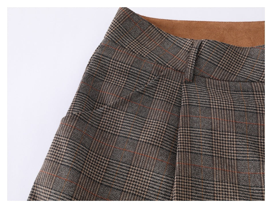 Close-up of brown-gray plaid trousers showing the waistband and front pocket opening.