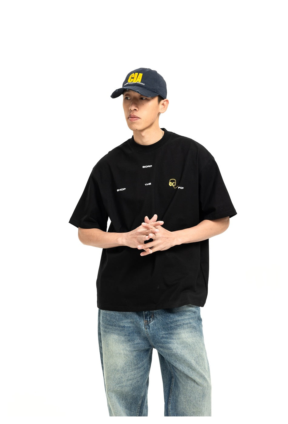 Model wearing a black oversized T-shirt with small white lettering and a yellow headphone chest graphic.