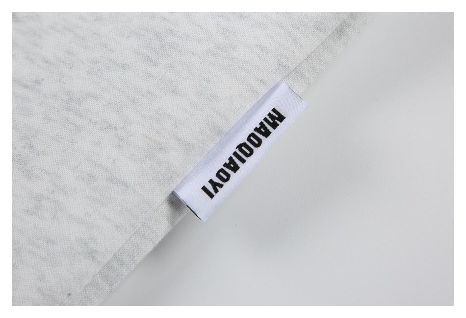 Close-up of a white brand tag sewn into the edge of the light gray heather shirt.
