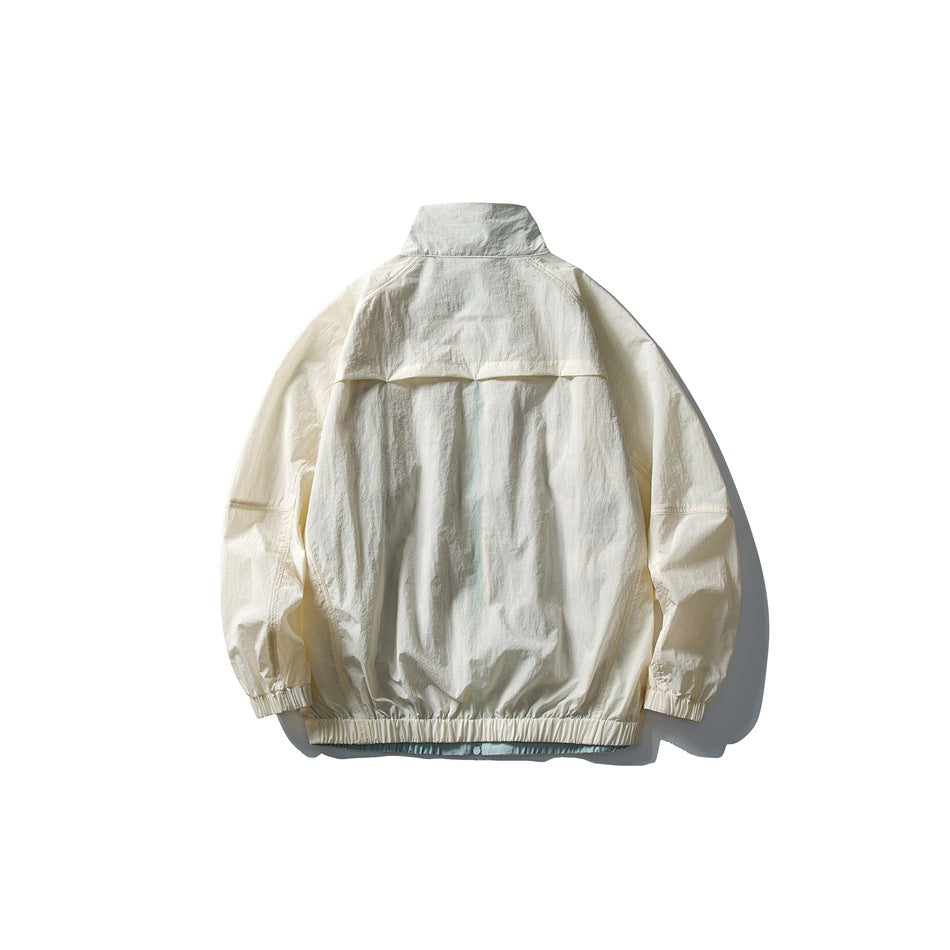 Back view of an ivory jacket laid flat, showing its stand collar, back yoke, gathered cuffs and elastic hem.