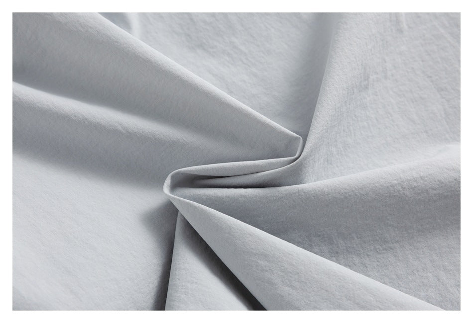 Close-up of light gray fabric folded into soft draped folds.