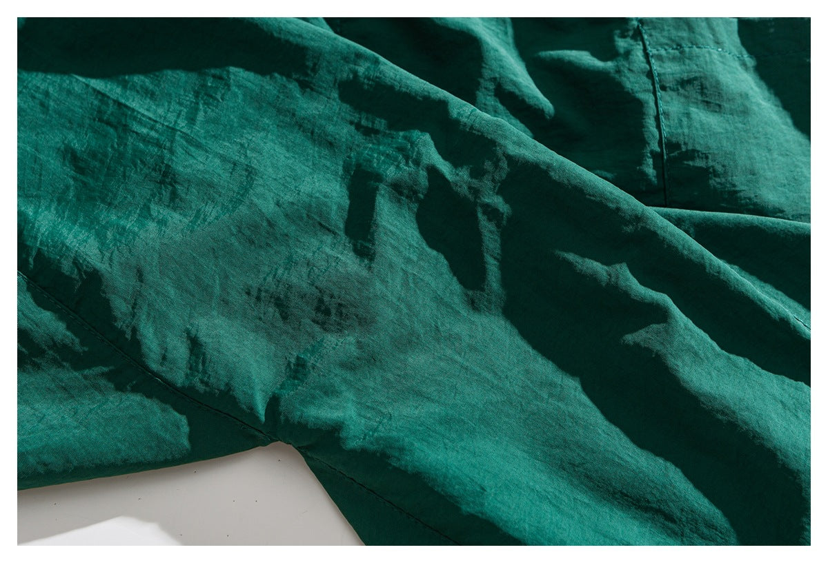 Close-up of the teal-green garment fabric, folds, and stitched seams.