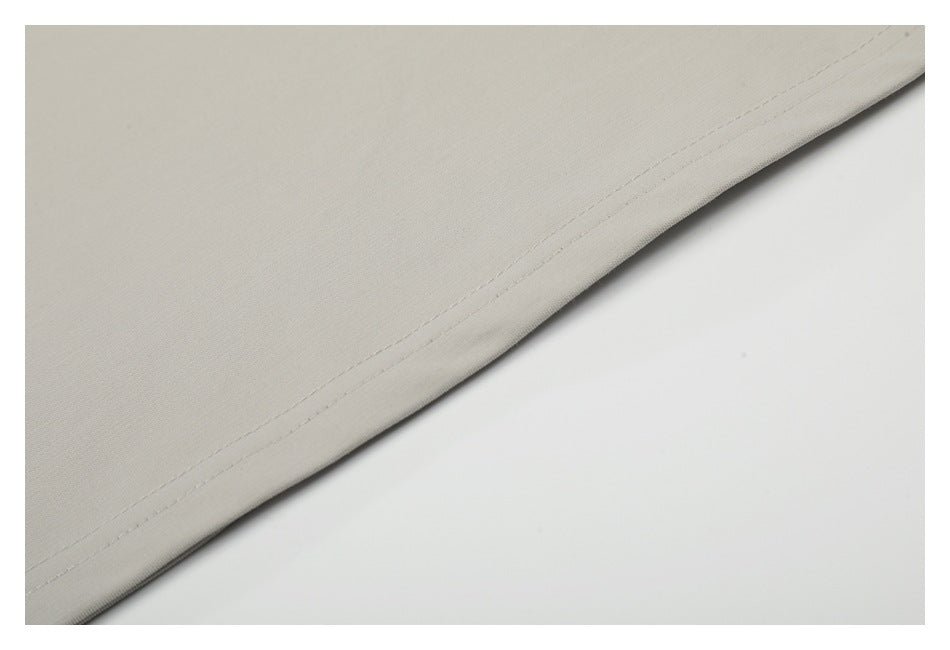 Close-up of a light beige garment hem with parallel rows of stitching.