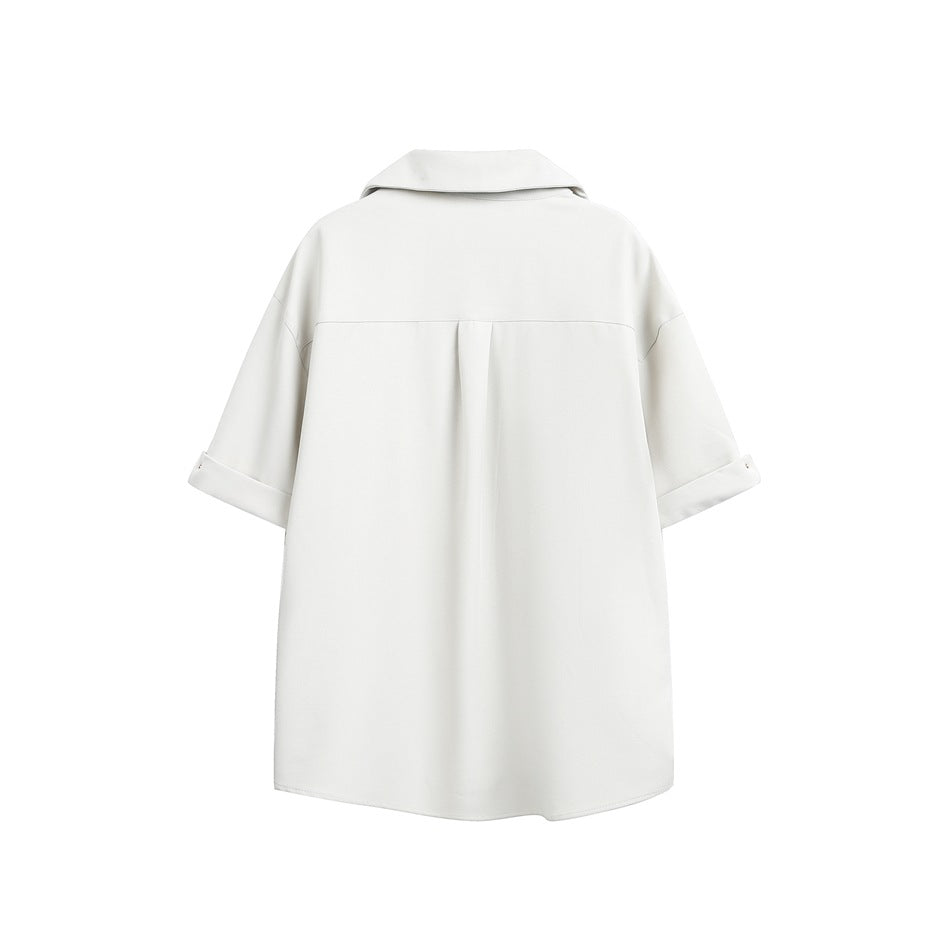 Back view of a loose white collared tunic with short cuffed sleeves and a center back pleat.
