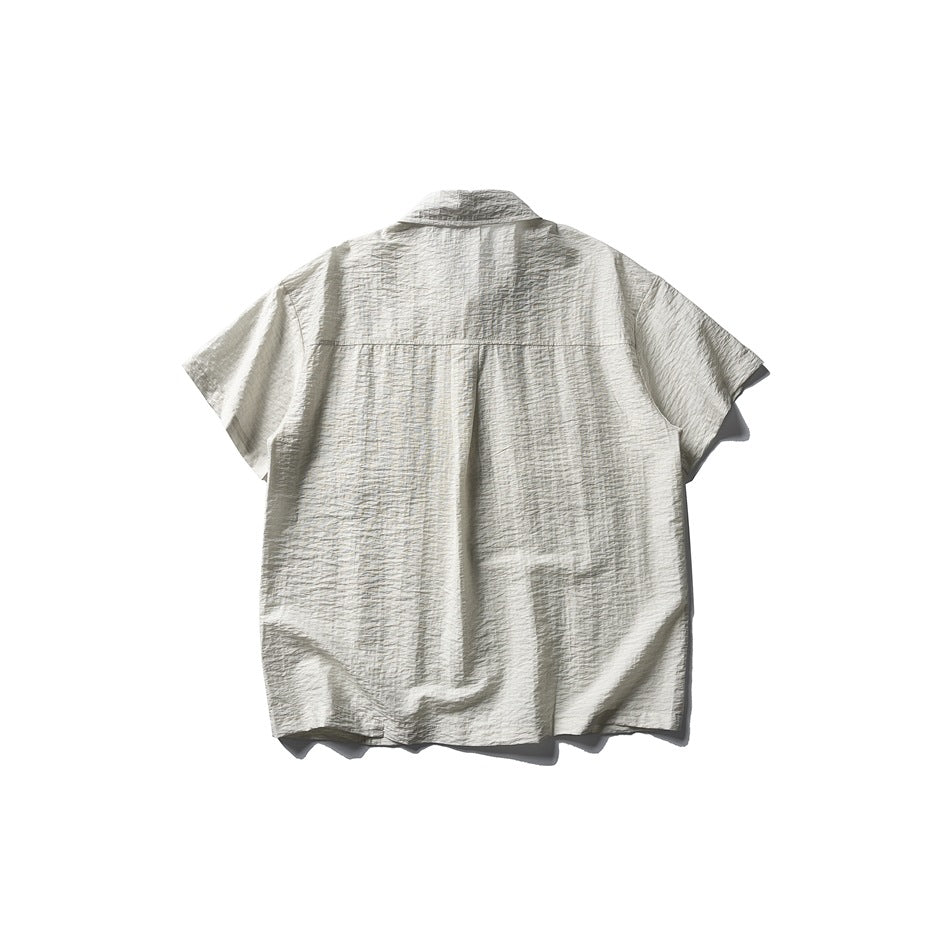 Back view of an off-white short-sleeve button-up shirt with a plain back and yoke seam.