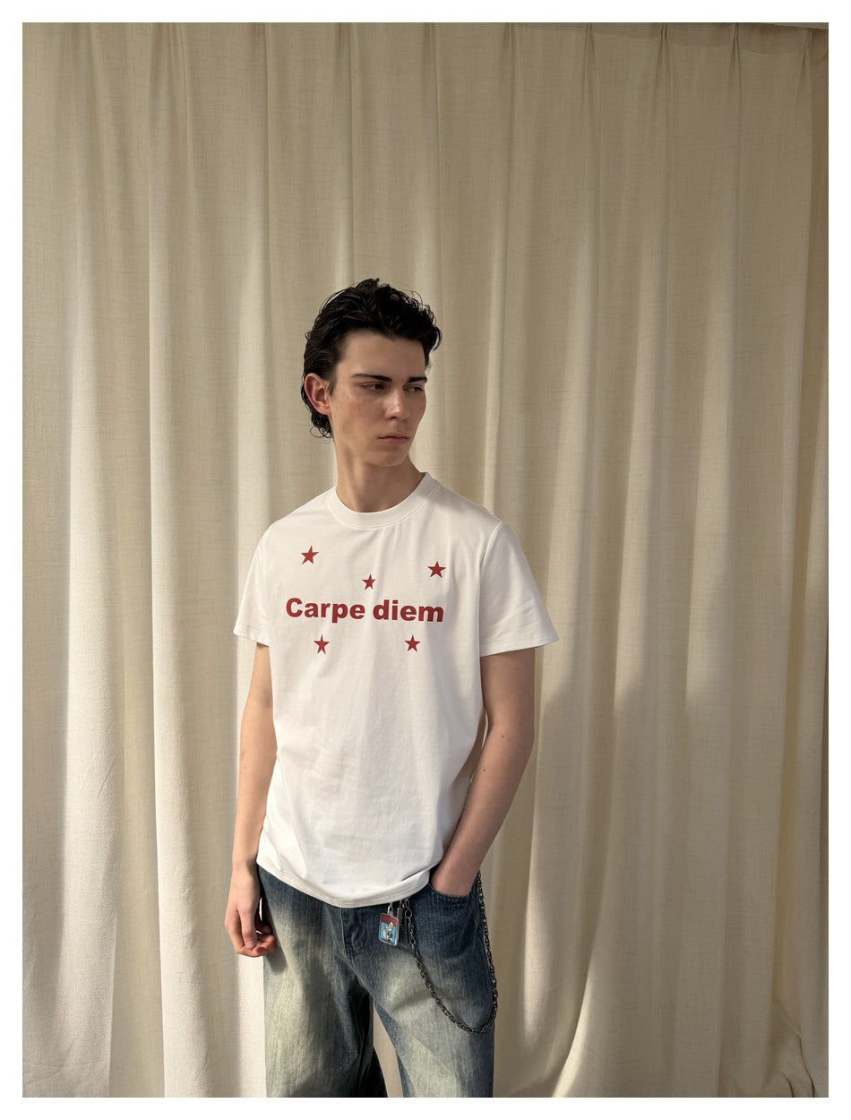Model wearing a white T-shirt with red Carpe diem lettering and stars, paired with faded jeans.