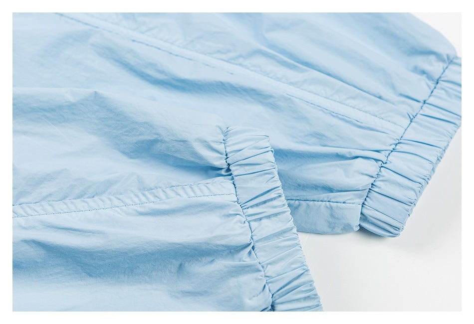 Close-up of gathered elastic edging and stitched seams on a light blue garment.