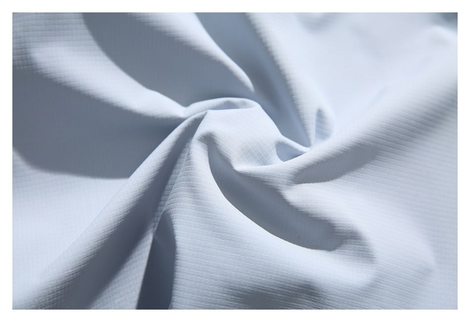Close-up of pale blue-gray fabric draped into soft folds, showing a fine, subtle grid texture.