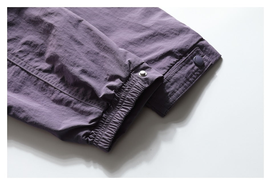 Close-up of a purple jacket sleeve cuff with elastic gathering, a snap tab, and visible stitching.