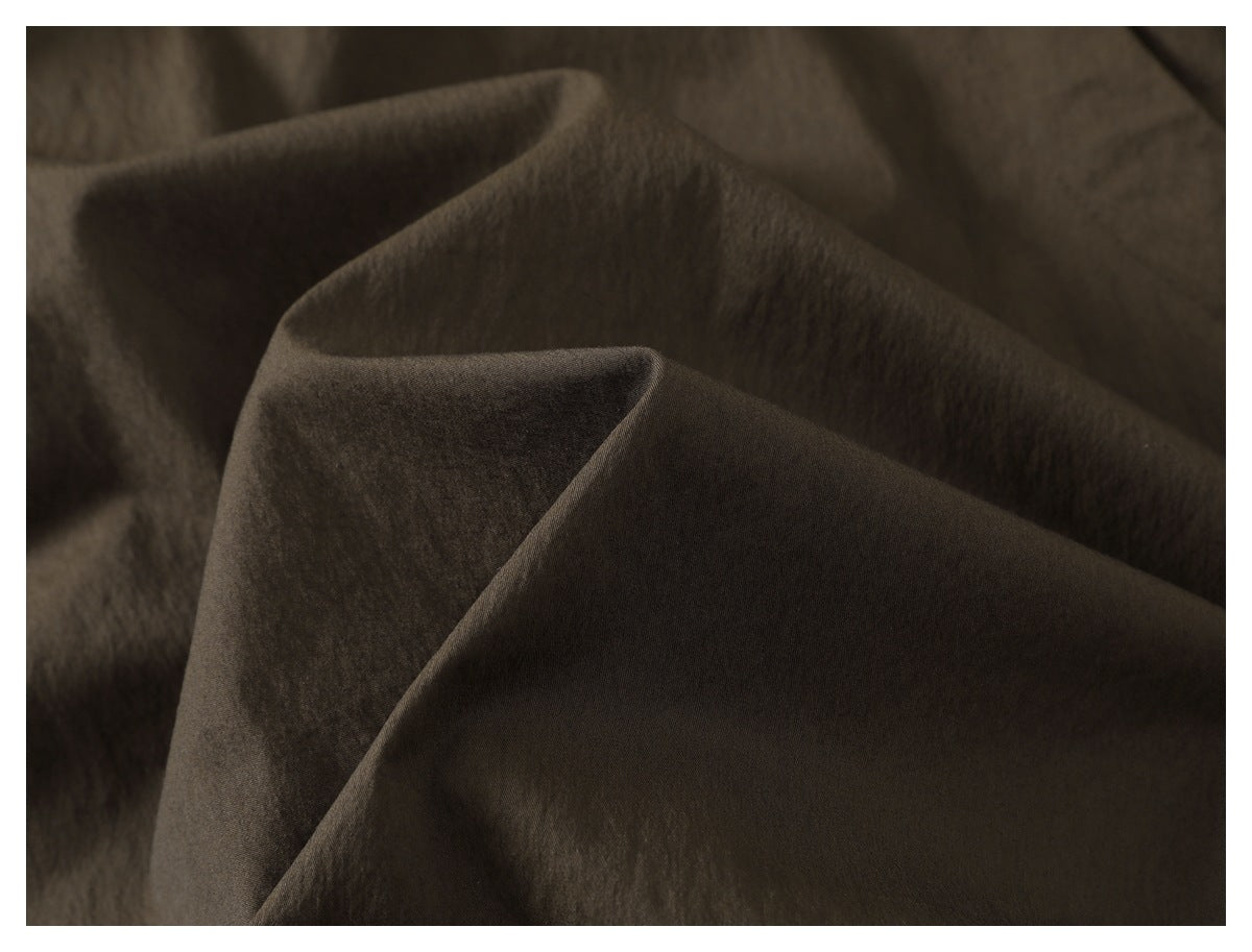 Extreme close-up of the dark olive-brown jacket fabric, showing its surface and folds.