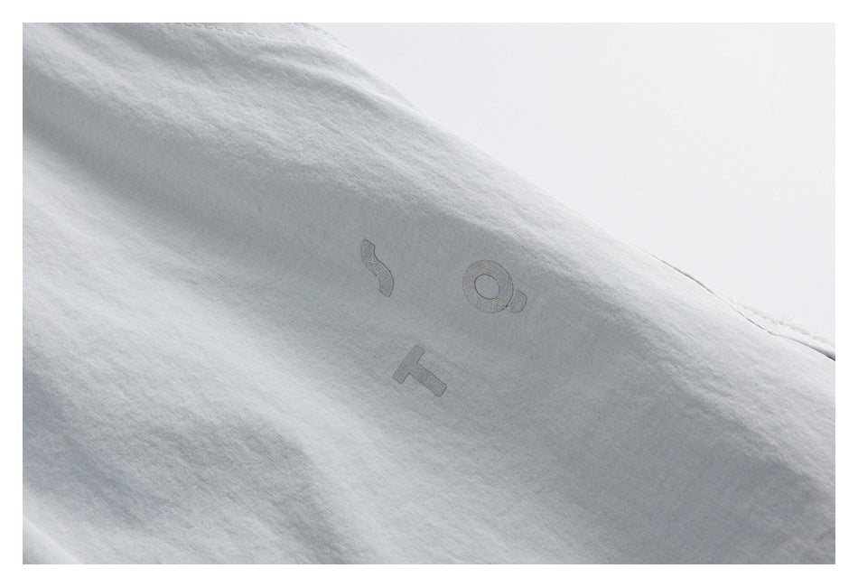 Close-up of light gray shorts with a subtle tonal graphic on the fabric.