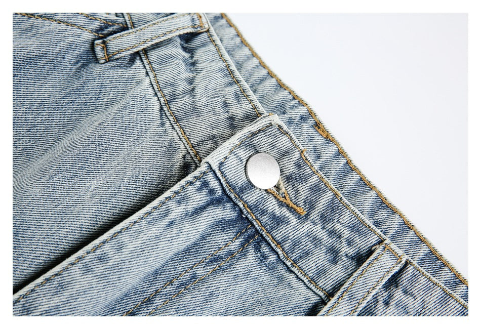 Close-up of light-wash jeans showing the waistband button, belt loop, and fly stitching.