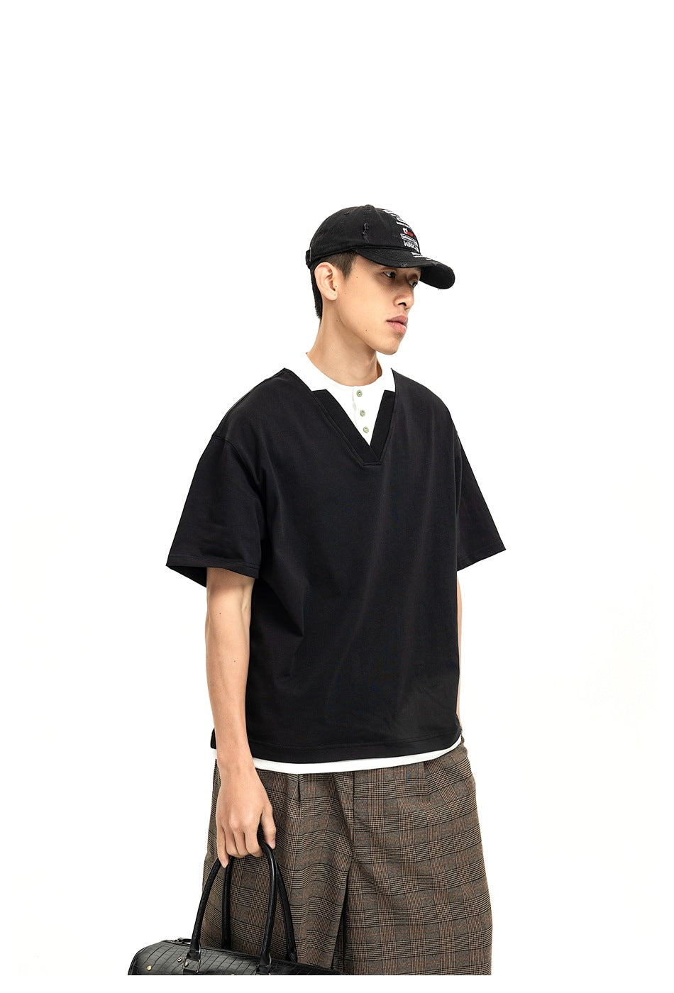 Model wearing a loose black short-sleeve V-neck top over a white button-placket shirt.