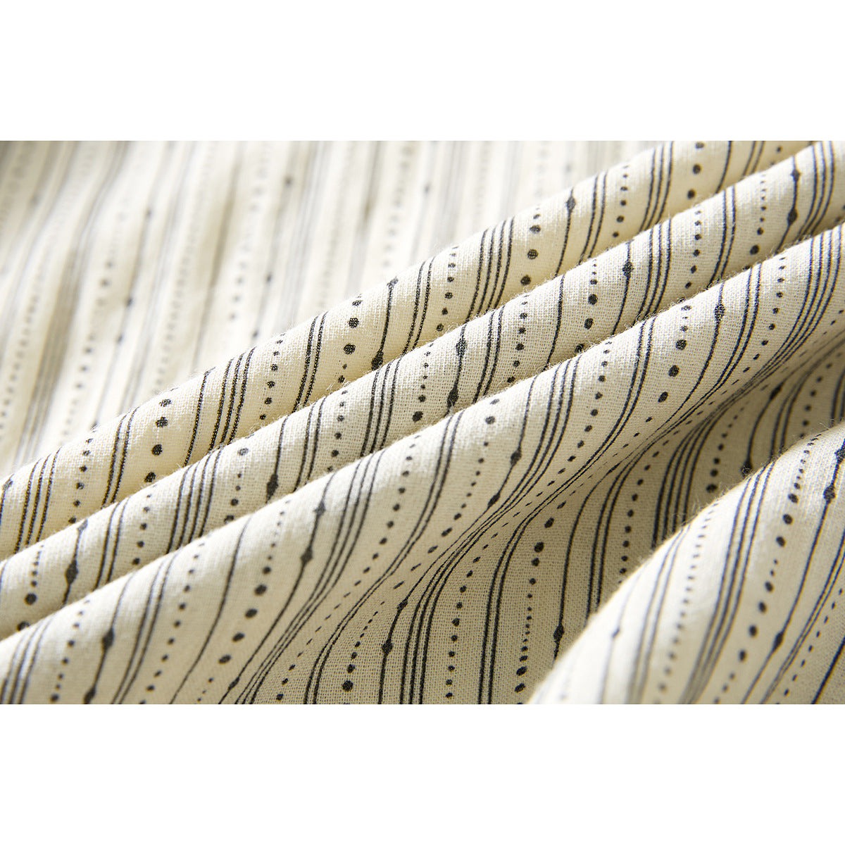 Close-up of ivory shirt fabric with fine black dotted stripes, draped in soft folds.