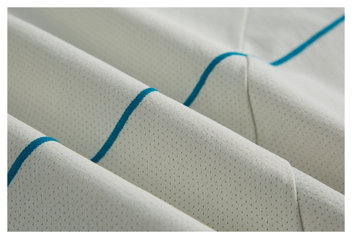 Close-up of ivory perforated fabric with curved teal piping and stitched seams.