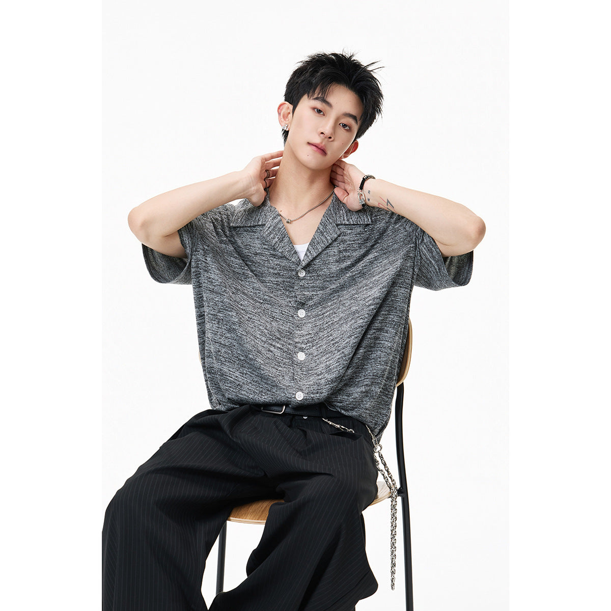 Model seated in a gray marled short-sleeve button-front shirt with a notched collar.