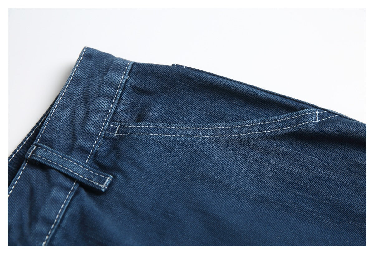 Close-up of dark blue jeans showing a belt loop, waistband seam and contrasting stitching.