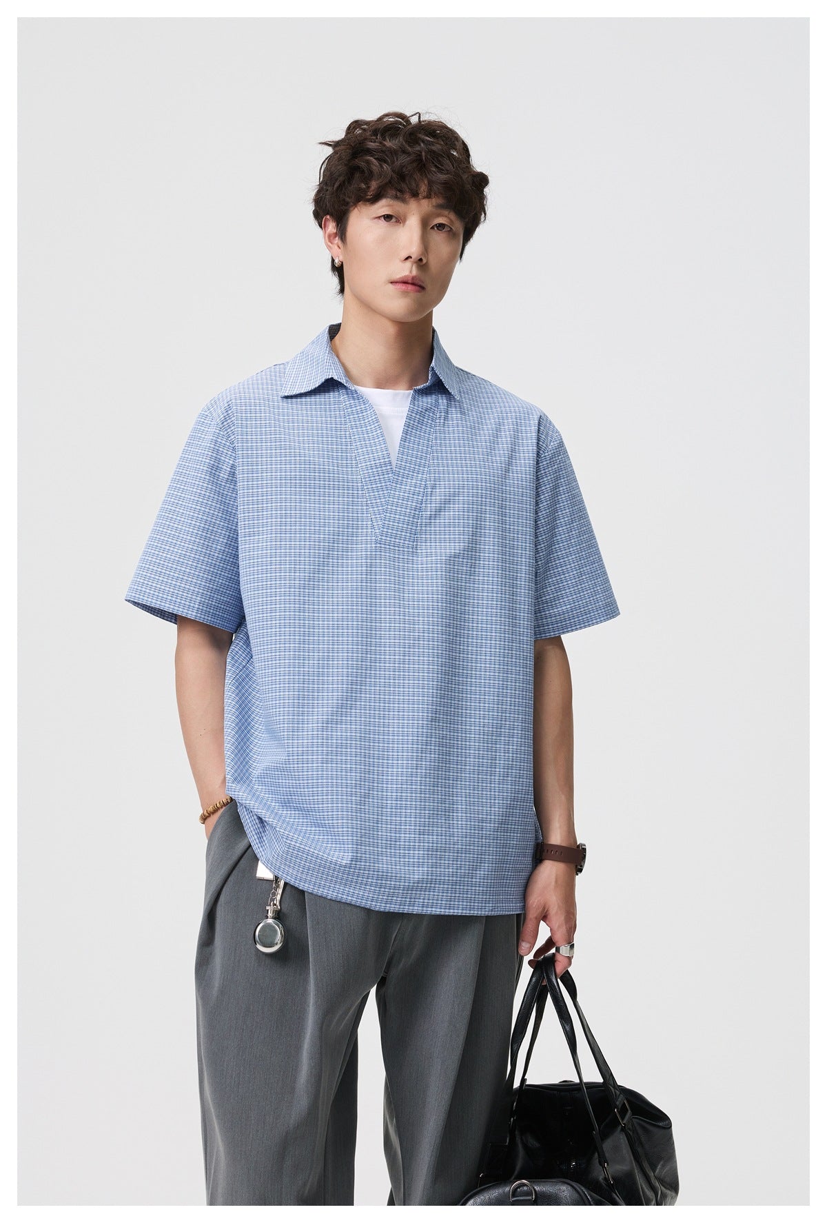 Closer front view of a man wearing a blue-and-white micro-check shirt with short sleeves and an open collar.