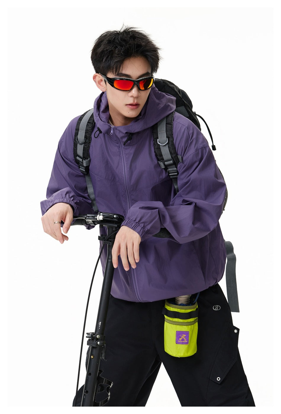 Close view of a model wearing a purple hooded zip jacket, black trousers, and a backpack.