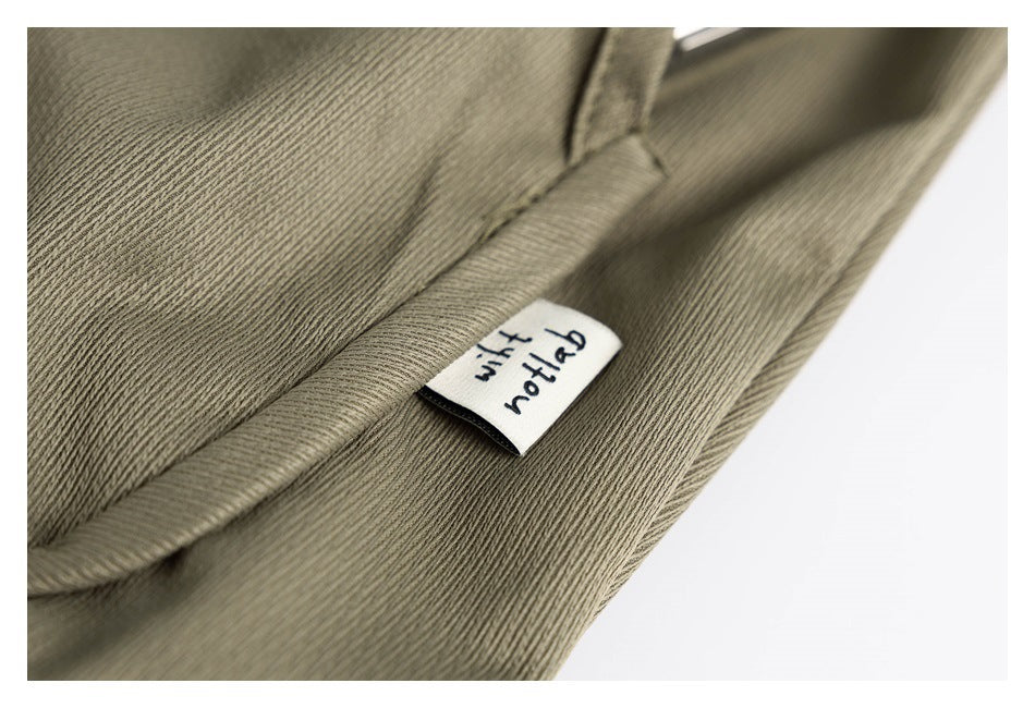 Close-up of olive fabric with a small white sewn label bearing dark lettering.