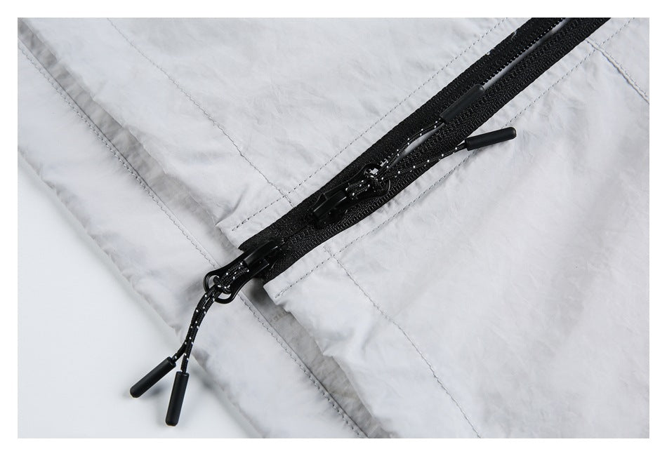 Close-up of black zipper tracks and corded pulls on a light gray jacket.