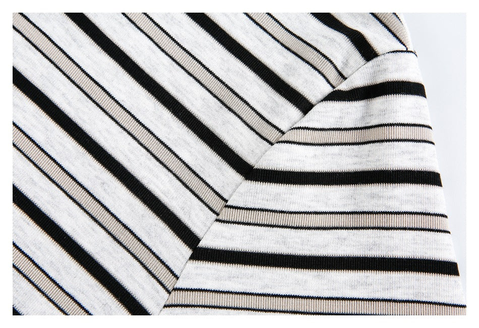 Close-up of a striped shirt sleeve meeting the body, with black and white stripes running in different directions.