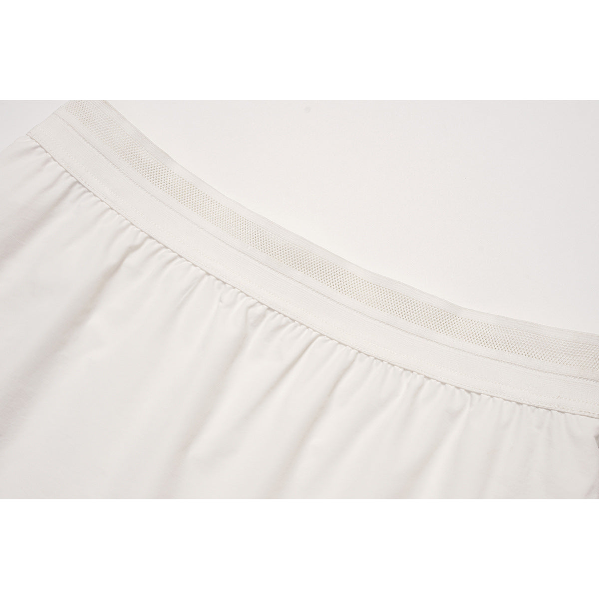 Close-up of a white skirt's wide textured elastic waistband and gathered fabric.
