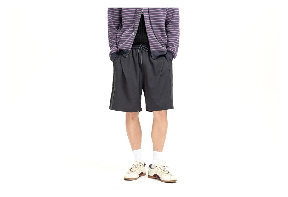 Cropped front view of a model wearing loose charcoal drawstring shorts.